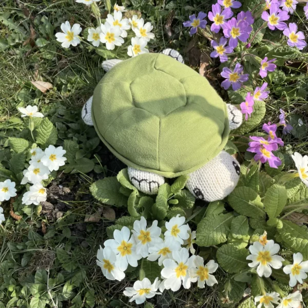 Peluche tortue coton bio se promène sur les fleurs